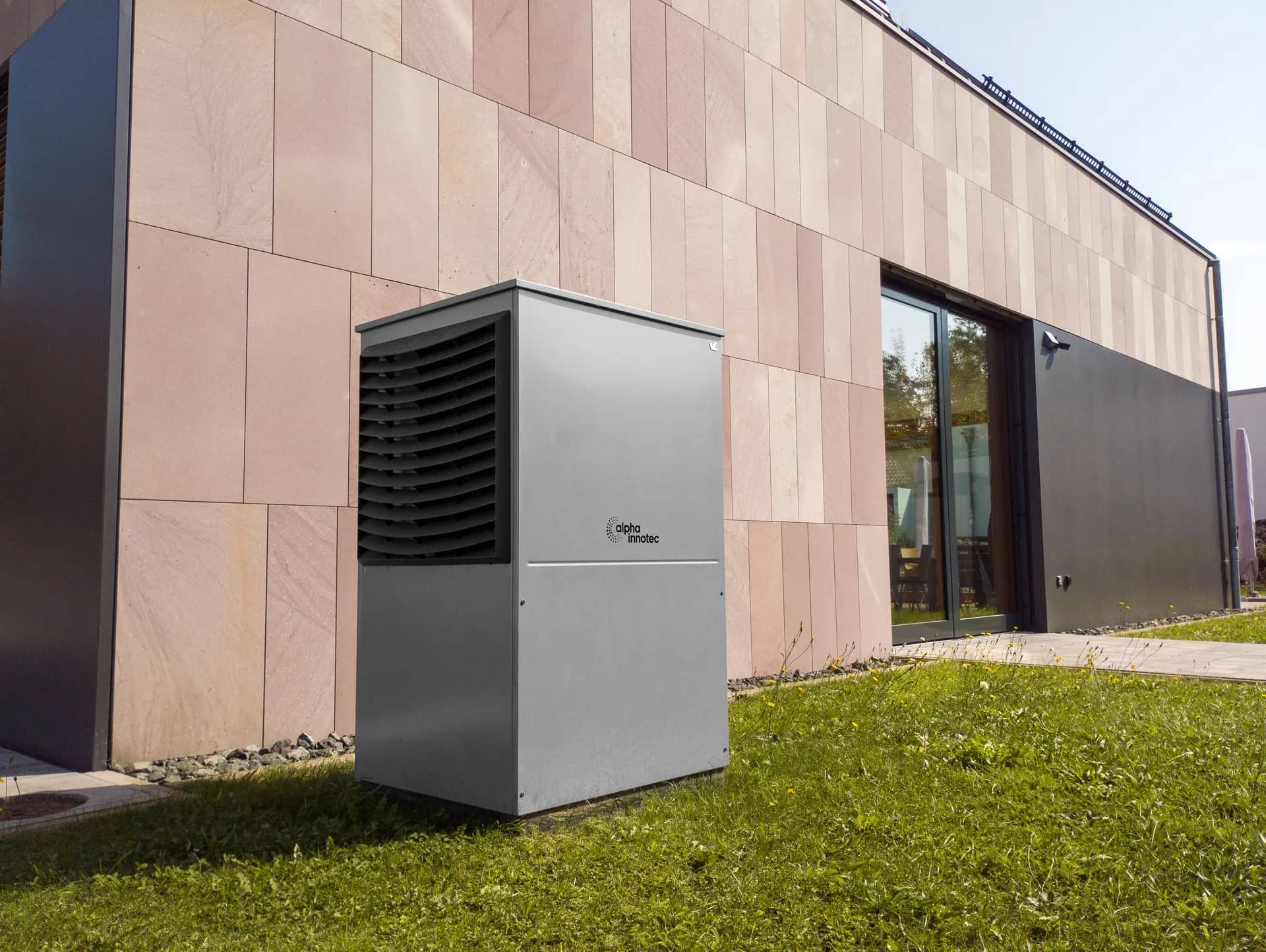 Air-source heat pump unit standing outside a modern house