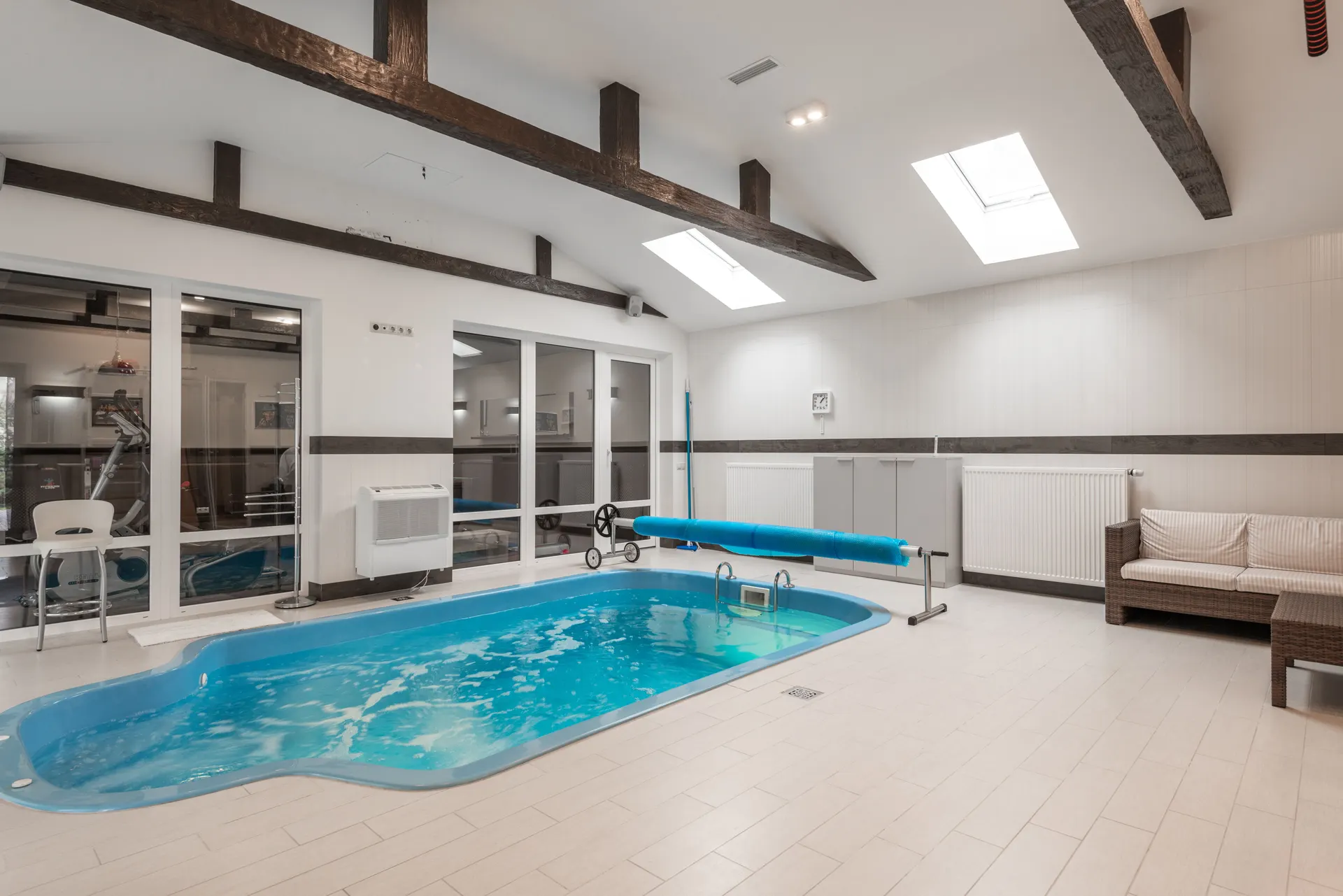 Indoor residential pool with a cover reel beside clear, balanced water